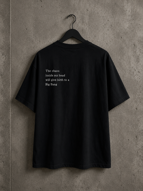 Vue arrière du t-shirt oversize noir Made in Killdzi avec citation brodée à la main, présenté sur cintre devant un mur en béton