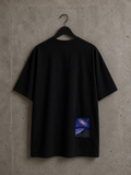 T-shirt oversize Made in Killdzi avec broderie artisanale galaxie au Needle Felting, présentation sur cintre avec fond en béton.