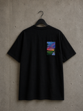 Dos d'un t-shirt oversize noir Made in Killdzi avec broderie artisanale colorée au Needle Felting représentant un paysage de coucher de soleil,, présenté sur cintre sur fond béton