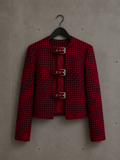 Veste courte upcyclée rouge et noirre à motif pied-de-poule, trois boucles métalliques sur le devant, présentée sur cintre sur fond béton. Création artisanale de la collection Chaos, Made in Killdzi.